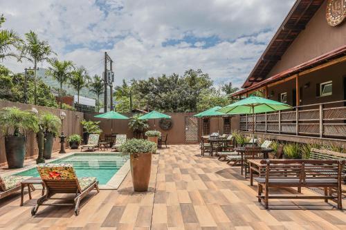 a patio with chairs and umbrellas next to a pool at Estaleiro Guest House in Balneário Camboriú