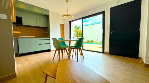 a kitchen with a table and green chairs in a room at DAYA LODGE. in LʼIsle-sur-la-Sorgue