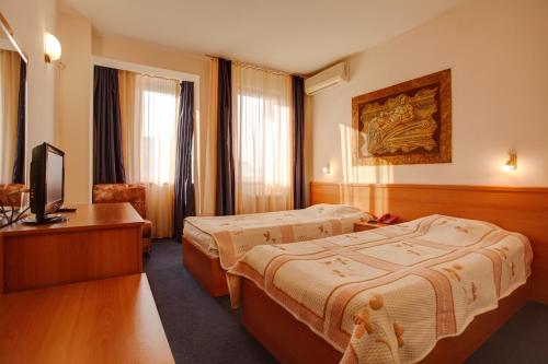 a hotel room with two beds and a television at Central Plaza Hotel in Sofia