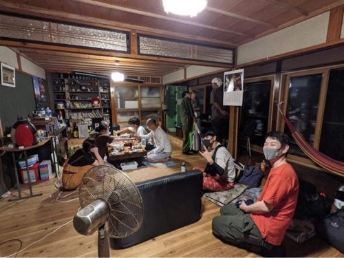 um grupo de pessoas sentadas no chão em uma sala em Obasute Guesthouse Nakaraya em Chikuma