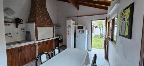 cocina con mesa y heladera blanca en Casa Tinta Roja 2 de 1 dormitorio en Villa Gesell