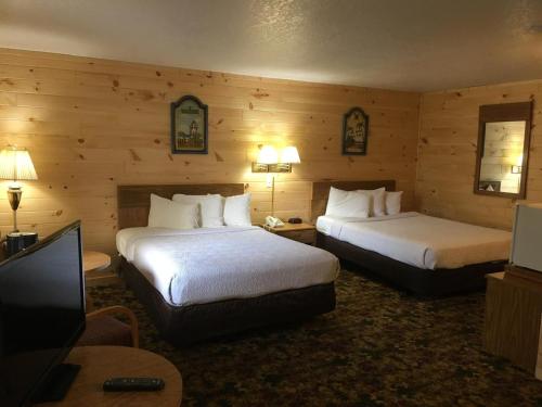 a hotel room with two beds and a flat screen tv at Great Mackinaw Beachfront Hotel in Mackinaw City