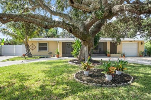 a house with a tree in a yard at Coastal Chic Home, Walk to Beach in Cocoa Beach