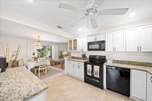 a kitchen with white cabinets and a black dishwasher at Coastal Chic Home, Walk to Beach in Cocoa Beach