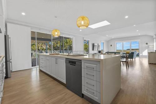 a kitchen with white cabinets and a dining room at Jewel on Crown in Paynesville