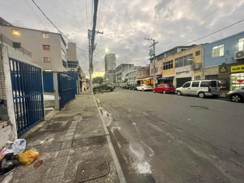 an empty city street with cars parked on the road at Pituba Suítes in Salvador