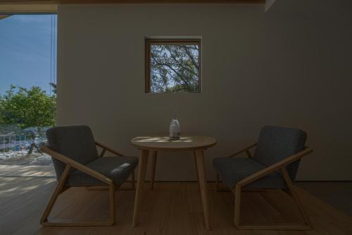 Dos sillas y una mesa en una habitación con ventana. en 星降る別邸WANASA, en Kannoura