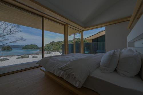 a bedroom with a bed with a view of the beach at 星降る別邸WANASA in Kannoura