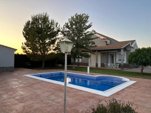 a swimming pool with a light pole in front of a house at Chalet Californiano con Piscina in Morón de la Frontera