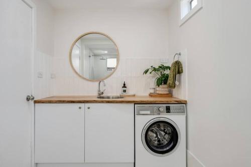 a bathroom with a washing machine and a mirror at The Gumnut Cottage in Wickham