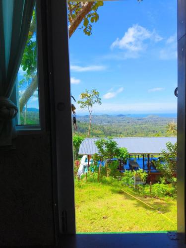 a window with a view of a house and a field at SZ Samui Glamping in Ban Sa Ket