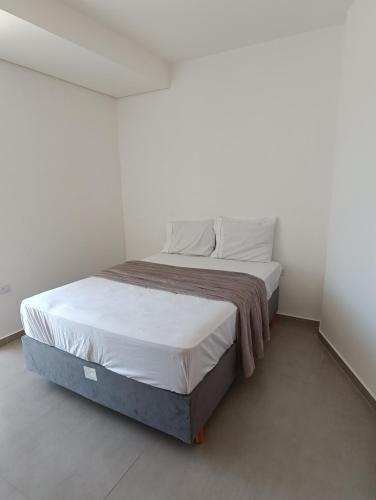 uma cama grande num quarto branco com em Residencial Mar Azul-suíte 12 em Pontal do Paraná