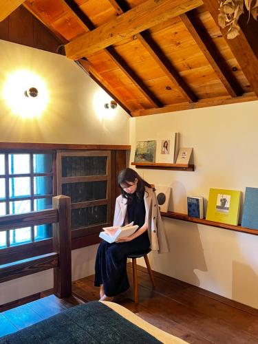 a woman sitting on a chair reading a book at The Bath & Bed Hayama in Hayama