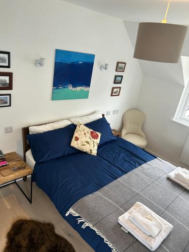 a bedroom with a blue bed and a table at Modern, centrally located, beach view flat in Pevensey