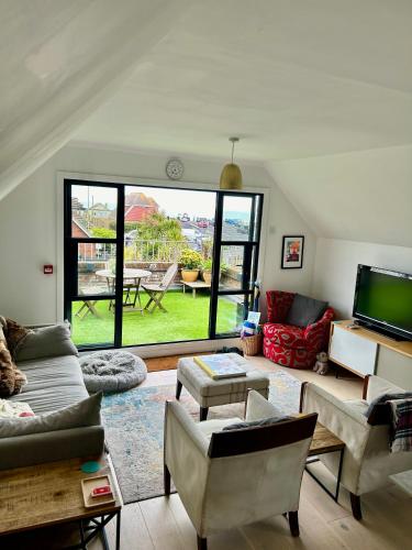 a living room filled with furniture and a large window at Modern, centrally located, beach view flat in Pevensey