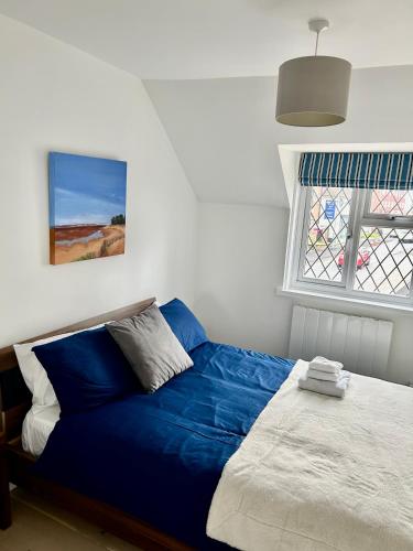 a blue bed in a bedroom with a window at Modern, centrally located, beach view flat in Pevensey