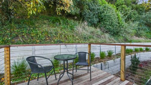 two chairs and a table on a wooden deck at Lake Metung in Metung