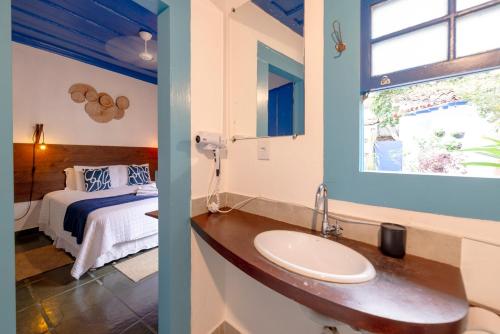 een badkamer met een wastafel en een bed in een kamer bij Casas do Pátio Pousada & Bar in Paraty