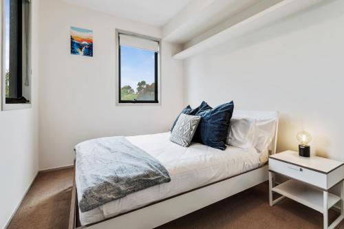een witte slaapkamer met een bed en een raam bij Convenient Kensington living Great Location in Melbourne