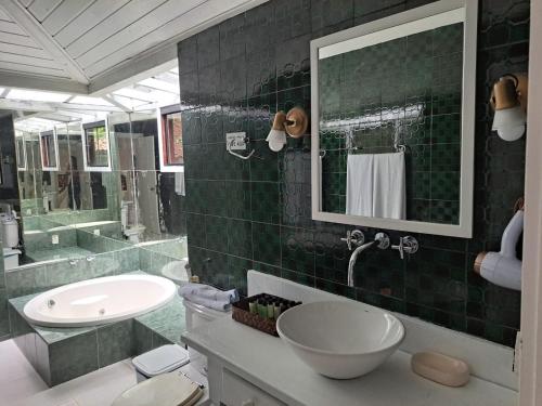 W wyłożonej zielonymi kafelkami łazience znajduje się umywalka i lustro. w obiekcie Barracuda Eco Resort Búzios w mieście Búzios
