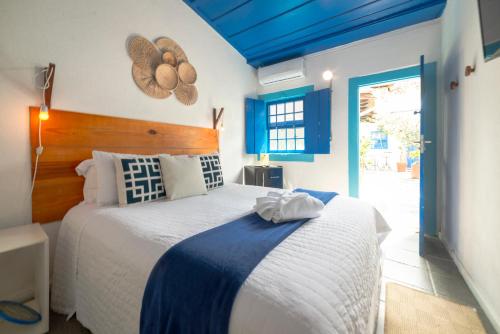 um quarto com uma cama grande e um tecto azul em Casas do Pátio Pousada & Bar em Paraty