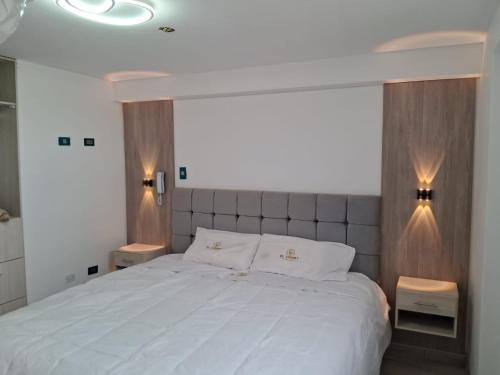 a bedroom with a large white bed with two night stands at Hotel El Virrey Suite in Espinar