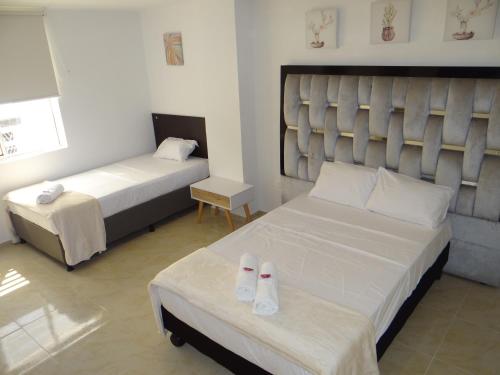 a hotel room with two beds with slippers on the bed at San Alejo in Tuluá