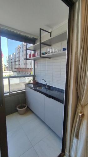 une cuisine avec un évier et une grande fenêtre dans l'établissement Apartamento em João Pessoa a 50 metros da Praia, à João Pessoa