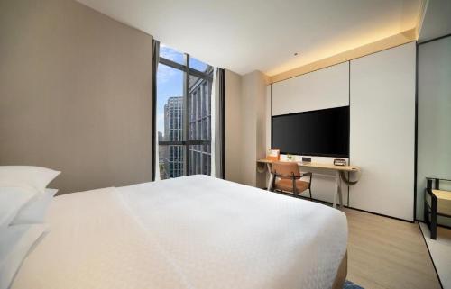 a hotel room with a bed and a desk with a tv at Four Points by Sheraton Chengdu, High-Tech Zone Exhibition Center in Chengdu