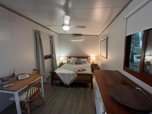 a bedroom with a bed and a desk and a sink at Three Rivers Cabin in Yandina
