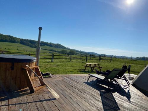 una terrazza con 2 sedie, un tavolo e un tavolo da picnic di Nuit insolite en Tipi avec bain nordique privatif, petits déjeuners inclus a Médonville
