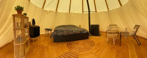 una camera da letto in una tenda con un letto e un tavolo di Nuit insolite en Tipi avec bain nordique privatif, petits déjeuners inclus a Médonville