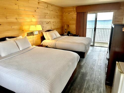 a hotel room with two beds and a balcony at Sunrise Beach Motel in Mackinaw City