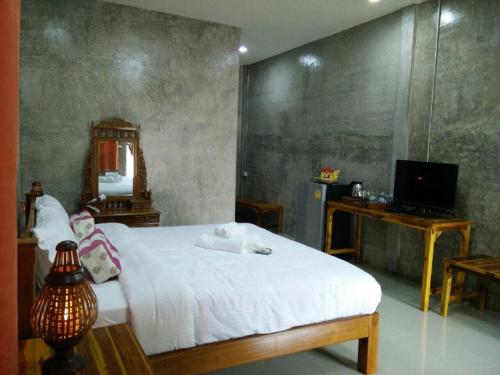 a bedroom with a bed and a desk and a television at Pottery Street House in Sukhothai