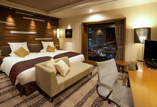 大阪市にあるホテル グランヴィア 大阪 JRホテル グループのベッド、椅子、テレビが備わるホテルルームです。