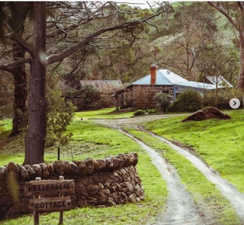 ein Feldweg, der zu einem Haus mit einer Steinmauer führt in der Unterkunft Ellerslie Cottage in Metcalfe