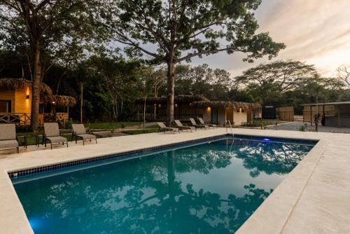 a swimming pool with chairs and a house at Dos Mares Venao Village in Playa Venao