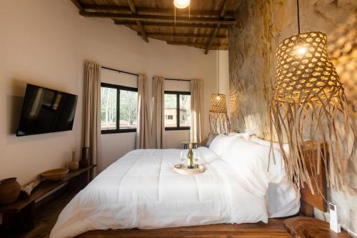 a bedroom with a large white bed with a tv at Dos Mares Venao Village in Playa Venao