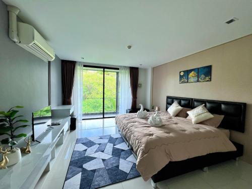 1 dormitorio con 1 cama grande y TV en The Pixels Cape Panwa Condo, en Phuket
