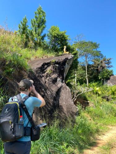 a man with a backpack taking a picture of a monkey on a rock at Dunali Mountains - Galaha in Galaha Town