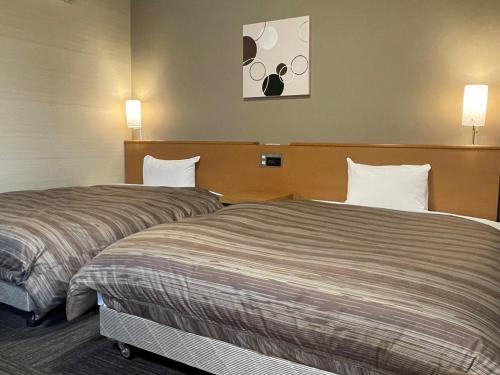 Dos camas en una habitación de hotel contigua en Hotel Route-Inn Kakegawa Inter, en Kakegawa