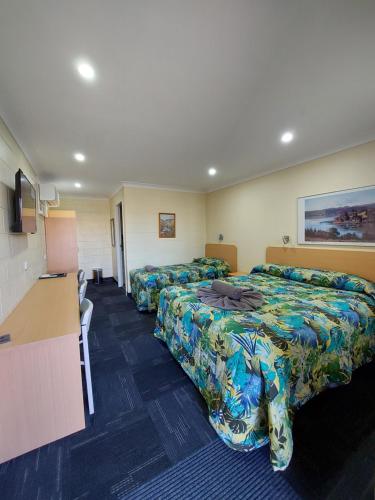 una camera d'albergo con tre letti e un bancone di All Seasons Motor Lodge a Dubbo