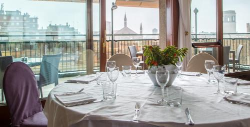 a table with glasses and a vase of flowers on it at Grande Albergo Roma in Piacenza