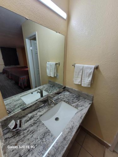 a bathroom with a sink and a large mirror at La Vista Motel in Brownsville
