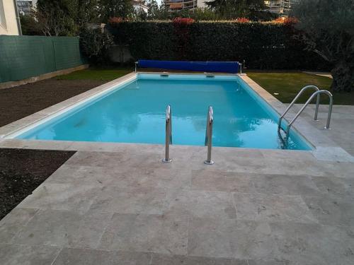 une piscine avec deux poteaux métalliques à l'intérieur dans l'établissement Grande maison luxe avec piscine, à Mandelieu-la-Napoule