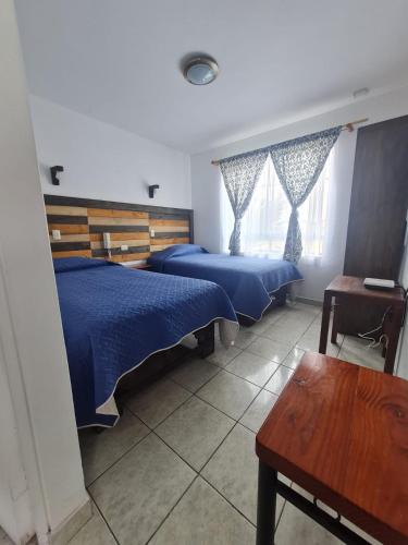 a bedroom with two beds and a table and a bench at Alto Chinchorro Hostel in Arica