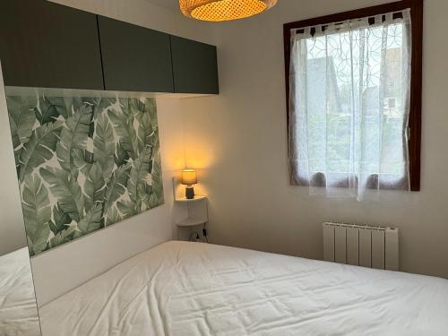 une chambre avec un lit avec une lampe et une fenêtre dans l'établissement Appartement 2P rénové à Cabourg, proche plage et thalasso, avec balcon et parking, 4 pers. - FR-1-487-368, à Cabourg