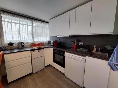 une cuisine avec des armoires blanches et des appareils électroménagers blancs dans l'établissement Charmant T2 près de la plage à Pontaillac - FR-1-550-77, à Royan