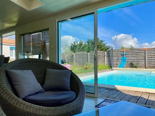 - une chaise en osier près de la piscine dans l'établissement Maison avec piscine privée, près de la plage, à Longeville-sur-Mer - FR-1-336-157, à Longeville-sur-Mer