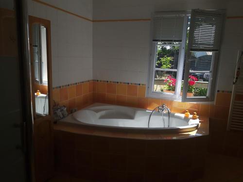 La salle de bains est pourvue d'une baignoire et de 2 fenêtres. dans l'établissement Maison avec piscine privée, près de la plage, à Longeville-sur-Mer - FR-1-336-157, à Longeville-sur-Mer